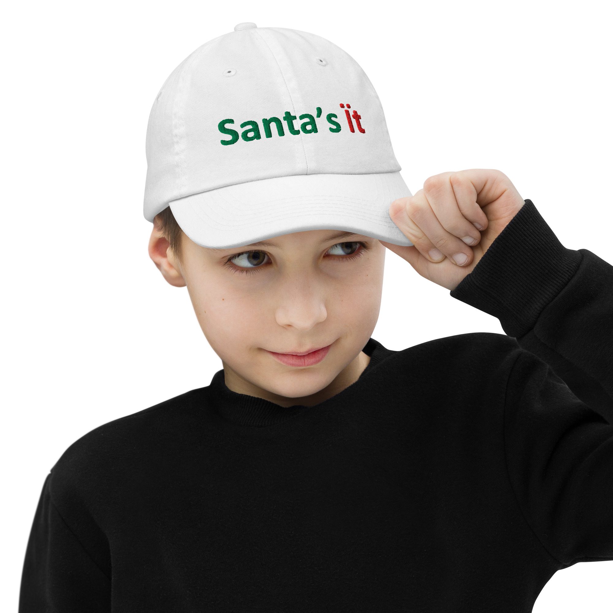Child wearing "Santa's it" white cap.