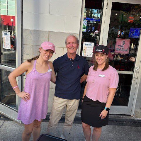 Three people smiling outside a restaurant.